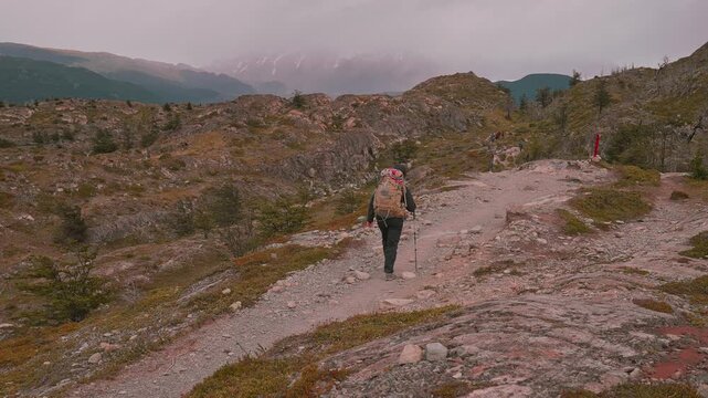 Following behind a backpack hiker on the Torres del Paine W Trek surrounded by rocky terrain, Patagonia, Chile  