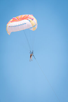 Person parasailing high above Phu Quoc sea with colorful parachute against bright tropical sky