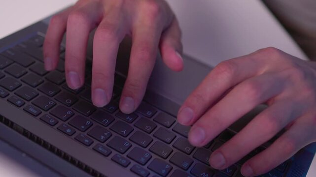 Hands typing on laptop keyboard in close view with fingers pressing keys, subtle movement and focused work at desk under cool indoor light during office routine