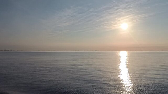 Stunning real-time video clip featuring a bright sun and soft wispy clouds over an open sea horizon