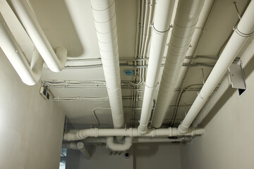Fototapeta premium industrial ceiling pipes installed and organized in white and gray interior building space with metal brackets and top-down perspective, neutral and functional.