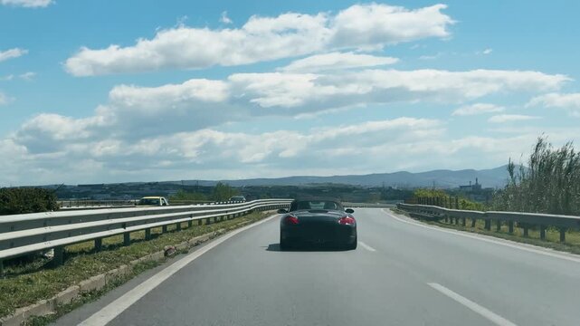 Sport Convertible Car Driving on Scenic Highway Under Blue Sky