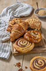 Fototapeta premium Various Freshly Baked Sweet Buns on Rustic Wooden Table and Cutting Board