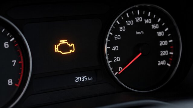 close-up of generic automobile instrument cluster with illuminated engine warning symbol
