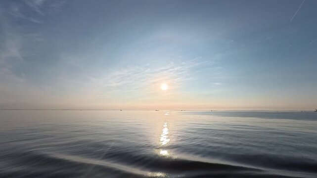 Cinematic video of brilliant morning sunlight reflection and powerful vessel wake waves on the ocean