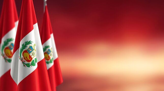 Three Peruvian flags waving in the wind with a red and orange sky in the background