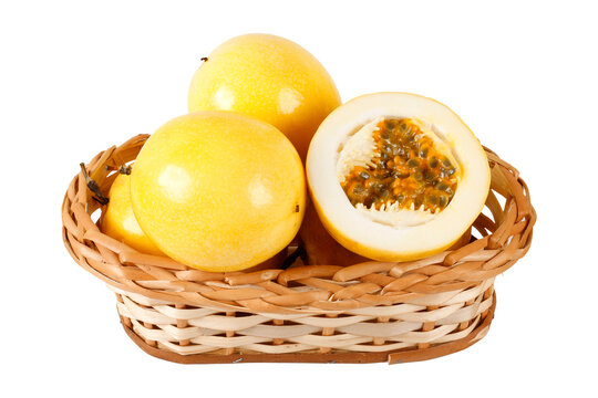 Fresh yellow passion fruits arranged in a wicker basket with one sliced fruit showing juicy pulp and seeds, isolated on a white background