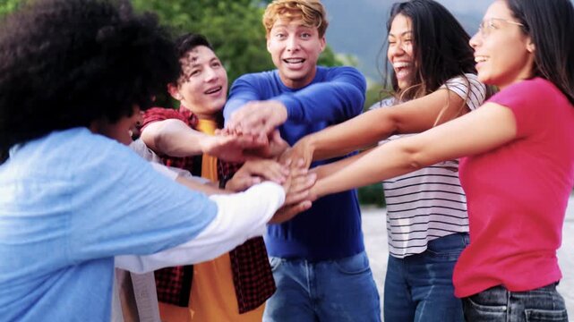 Young multiracial community of friends having fun stacking hands together outdoor - Friendship and diversity concept
