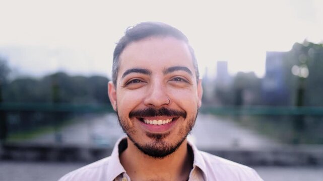 Young hispanic man smiling front of camera in the city