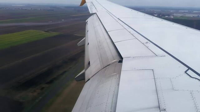 Airplane Wing View During Landing Approach Over Fields