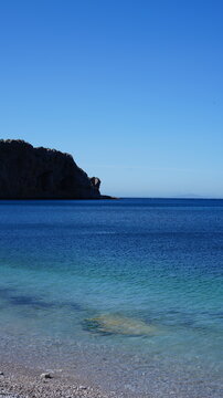Crystal Clear Blue Belyounech Sea and Rocky Coastline Under Clear Sky
