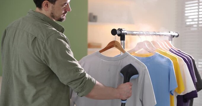 Man steaming t=shirt with modern steamer at home, closeup