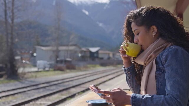 A young traveller checks her mobile phone whilst waiting at a train station