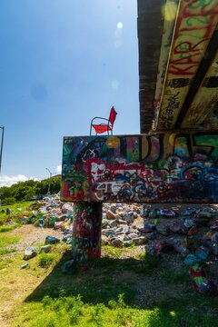 Red chair on graffiti-covered ledge beneath painted highway bridge