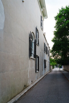 Historic stucco house with black shutters along quiet alley