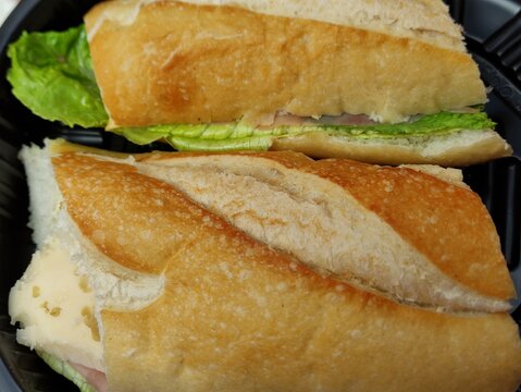 Dos mitades de una torta mexicana con jam&oacute;n, queso y lechuga en un plato.Two halves of a Mexican torta with ham, cheese, and lettuce on a plate(29).