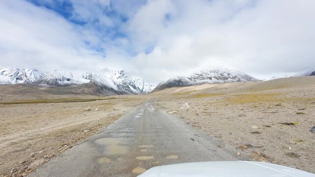 Driving on the offroad way to Ama Drime Snow Mountain in Shigatse, Tibet, China, the rutted mud road full of deep muddy craters and horribly bumpy. POV from car, 4k real time footage travel concept.