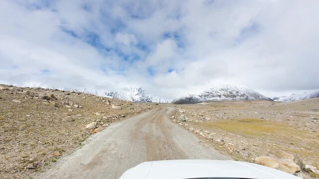Driving on the offroad way to Ama Drime Snow Mountain in Shigatse, Tibet, China, the rutted mud road full of deep muddy craters and horribly bumpy. POV from car, 4k real time footage travel concept.