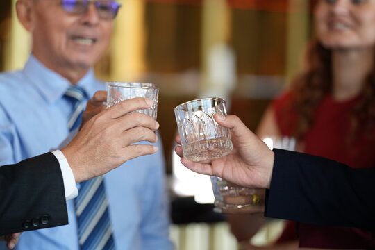 A group of friends at the hotel bar, clinking whiskey glasses in celebration at an elegant hotel cocktail bar, showcasing world class hotel service and style, looking calm and content.