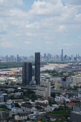 Obraz premium A wide view over a dense modern city packed with skyscrapers and office towers over the capital of Thailand in Southeast Asia, under a bright clear sky, in warm daylight with crisp detail.