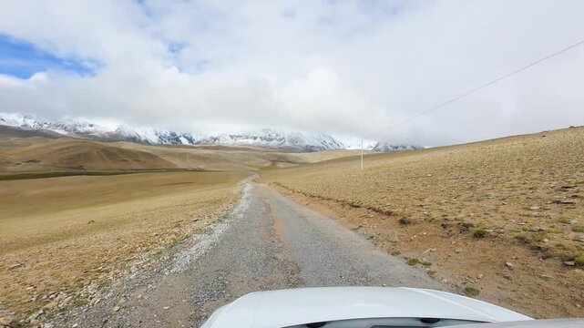 Driving on the off-road way to Ama Drime Snow Mountain in Shigatse, Tibet, China, the rutted mud road full of deep muddy craters and horribly bumpy. POV from car, 4k fast motion footage travel concept