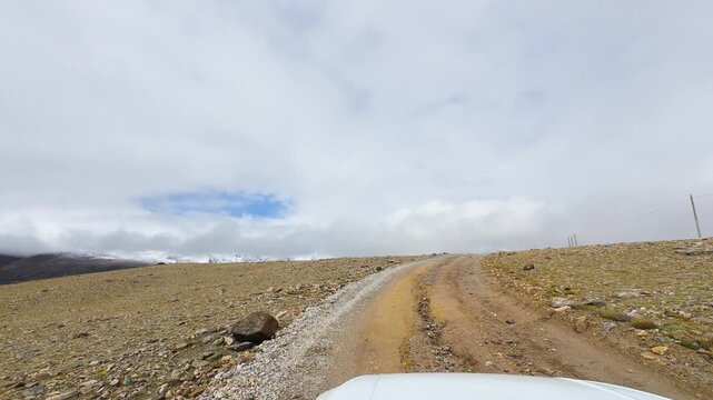 Driving on the offroad way to Ama Drime Snow Mountain in Shigatse, Tibet, China, the rutted mud road full of deep muddy craters and horribly bumpy. POV from car, 4k real time footage travel concept.