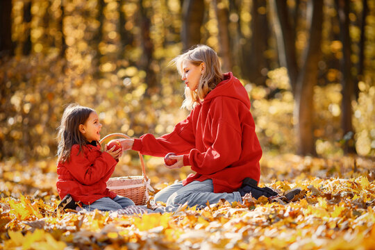 Mother and daughter sitting on a blanket in autumn forest