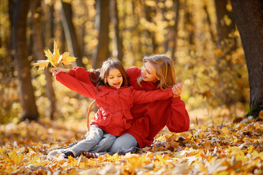 Mother and daughter sitting on a blanket in autumn forest