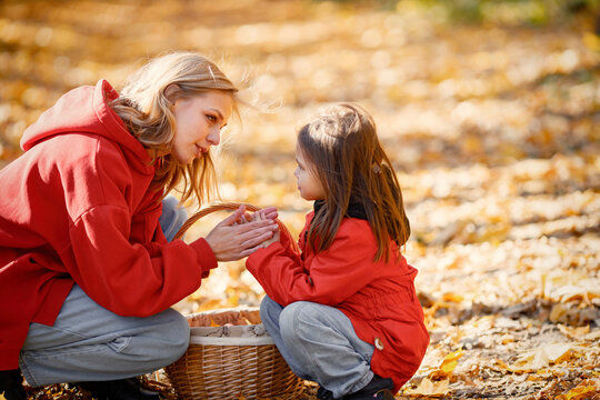 Mother and daughter walking and playing in autumn forest