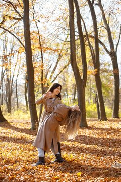 Two girls friends spending time together in autumn park