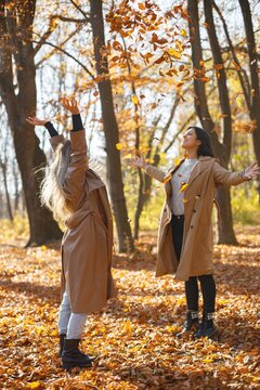 Two girls friends spending time together in autumn park