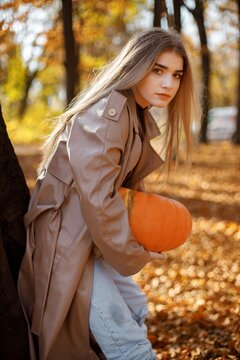 Portrait of a young woman posing for a photo in autumn park