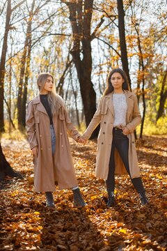 Two girls friends spending time together in autumn park