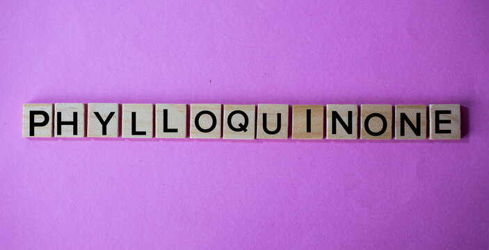 Phylloquinone Word Spelled with Wooden Letter Tiles on Pink Background
