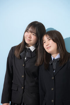 水色背景で本人女子高生や中学生2人で　仲良しで寄り添う友情や友達、仲間や親友イメージ