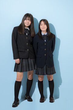 水色背景で本人女子高生や中学生の全身　2人でカメラ目線笑顔の全身　受験や青春、合格やオープンキャンパスイメージ