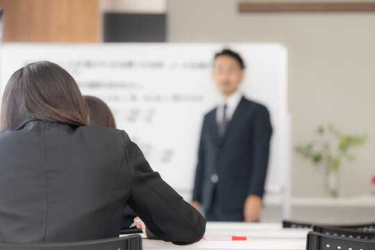 黒板を見ながら、塾や授業で手を挙げる中学生、女高校生と教師の学校の教室での様子　顔無しの後姿