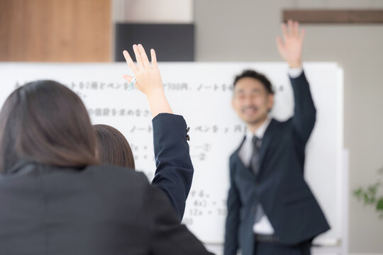 黒板を見ながら、塾や授業で手を挙げる中学生、女高校生と教師の学校の教室での様子