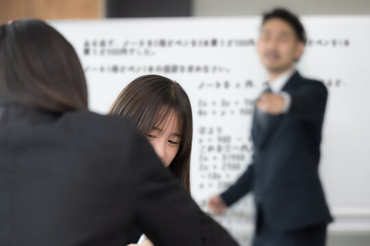 授業中におしゃべりの私語をして教師に注意される女子高校生　学校教育と教室での指導風景　内申点、生徒指導のメージ