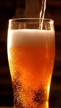 Slow motion video of golden craft beer being poured into a chilled glass