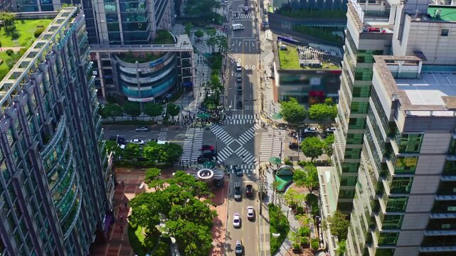 An aerial drone view of a busy multi-lane road in Seoul surrounded by urban buildings and green trees on both sides.