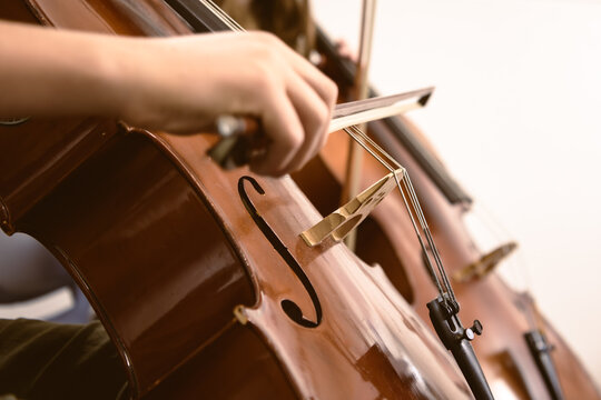 Close-up of a musician playing the cello with focus on the bow and strings - horizontal