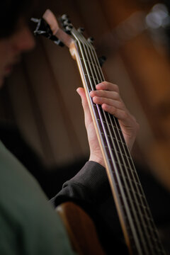 Close-up of a person playing a bass guitar in a cozy setting - vertical