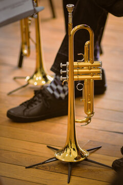 Close-up of a golden trumpet resting on a stand in a music setting- vertical