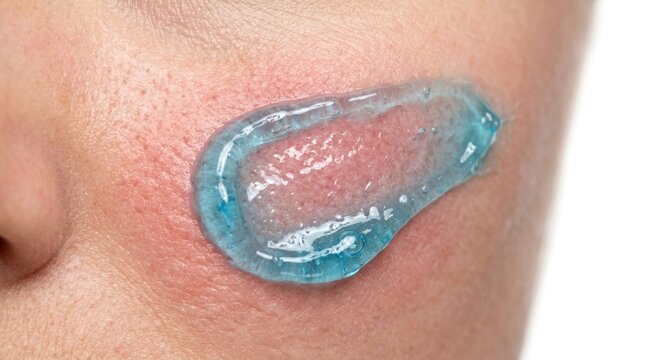 Thick smear swatch of soothing blue copper peptide gel mask on woman cheek skin for barrier repair