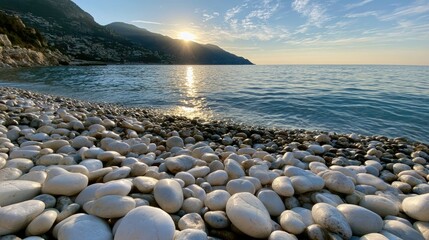 Obraz premium Sunlit seascape over a smooth, rocky beach as gentle waves lap the shore