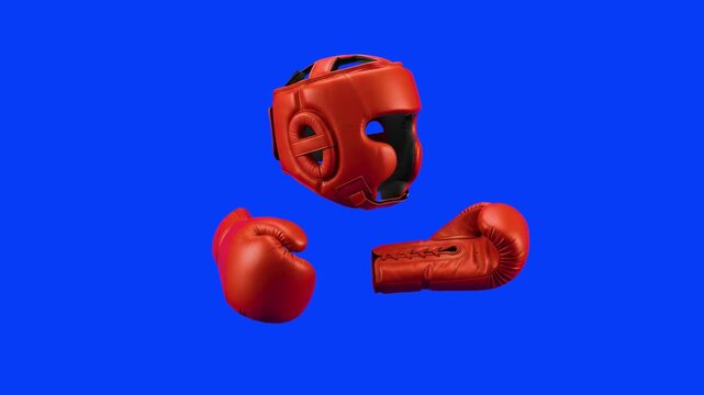 A set of protective red boxing equipment, including a head guard helmet and two matching boxing gloves, floats and rotates slowly. This sports safety gear is isolated on a chroma key blue screen.
