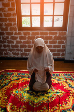 Muslim woman praying for Allah muslim god at room near window. Hands of muslim woman on the carpet praying in traditional wearing clothes, Woman in Hijab, Carpet of Kaaba. Concept of religion Islam
