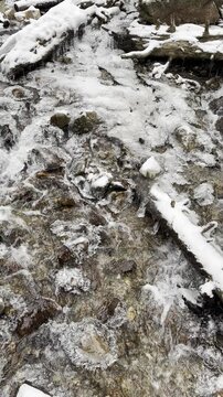 river stream flowing over snow and ice covered rocks and trees