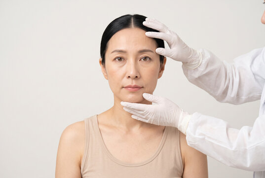 ベージュのトップを着た人物が美容医療の診察を受けるフェイシャルチェックアップの医療イメージ